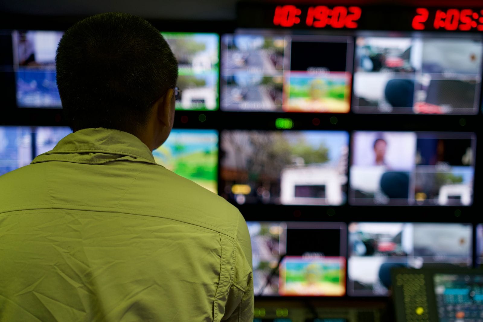 Cilvēks vadības telpā skata vairākus videonovērošanas monitorus